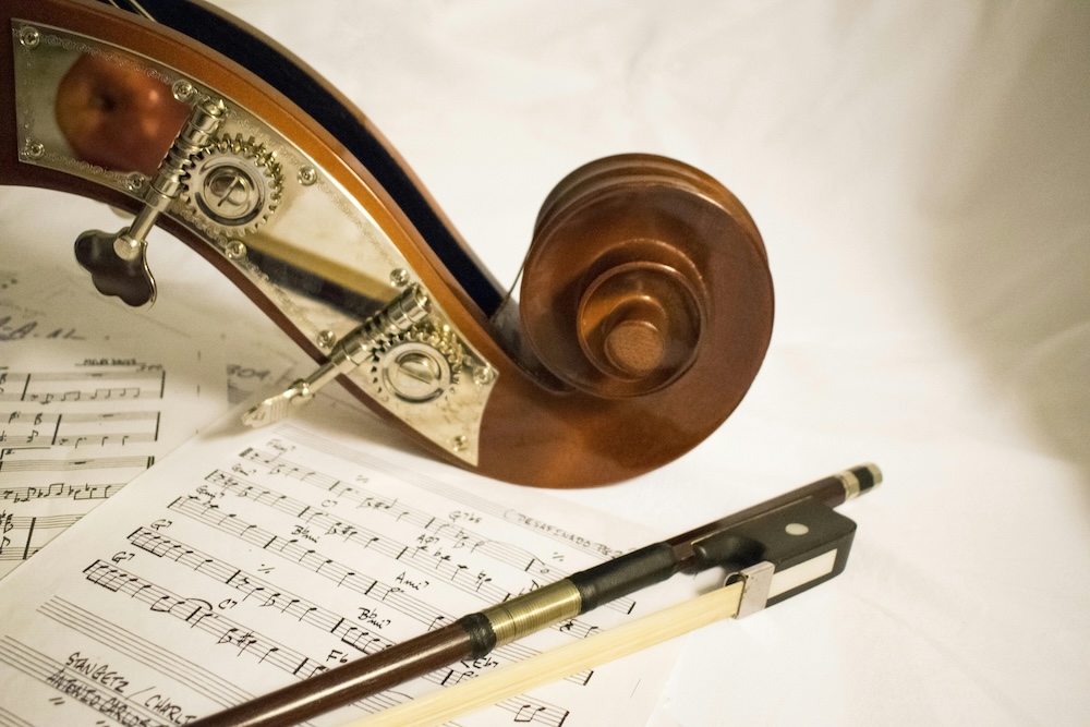 Violin bow resting on sheet music beside a violin scroll